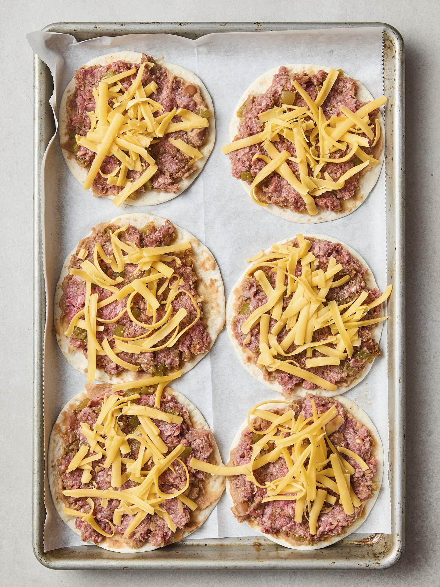 Cheese sprinkled on top of beef mixture on tortillas.