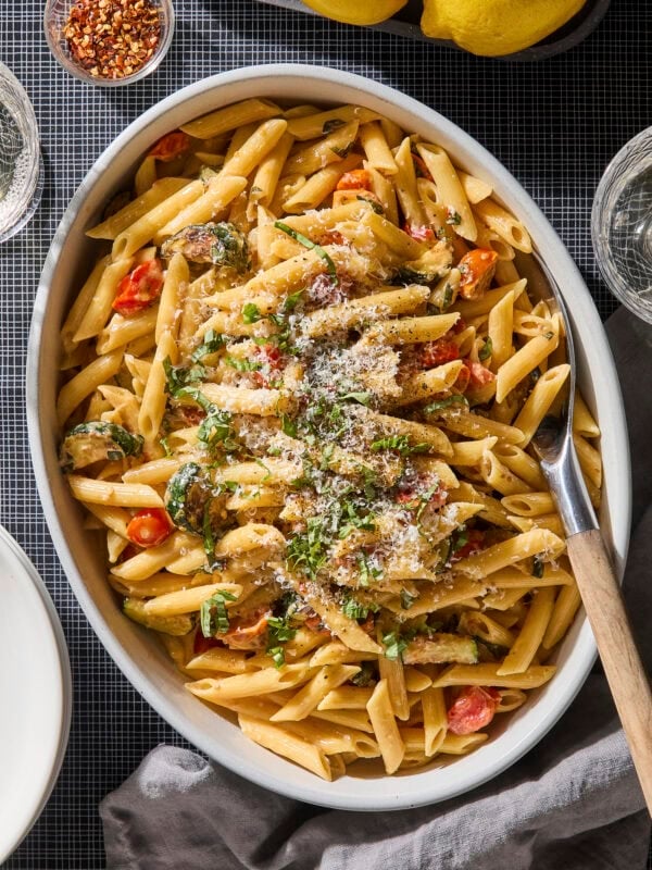 Serving bowl with creamy pasta with zucchini with basil and Parmesan on top.
