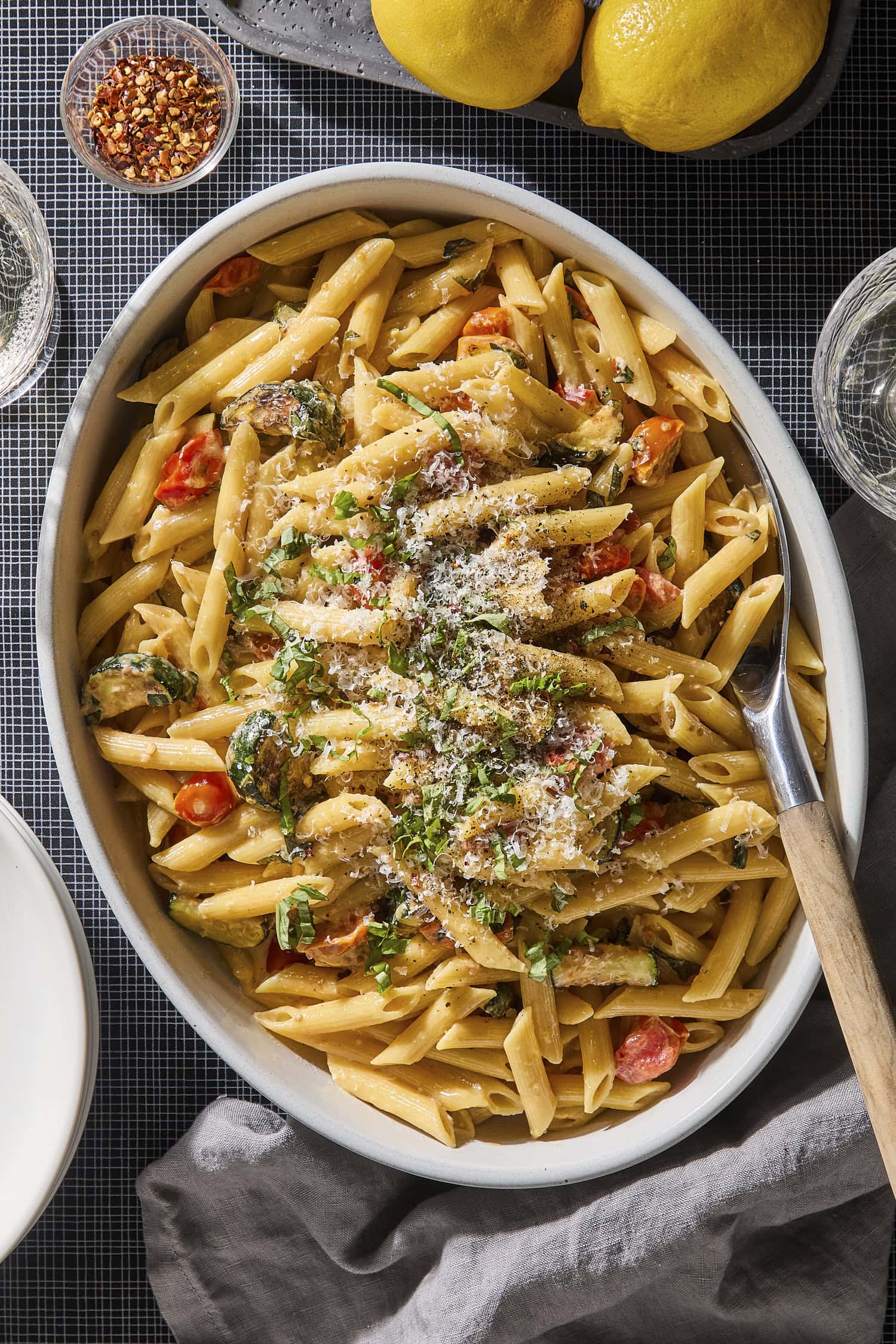 Serving bowl with creamy pasta with zucchini with basil and Parmesan on top.