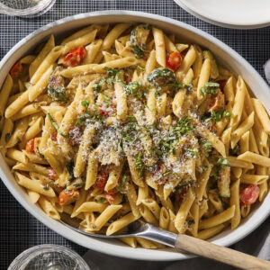 Pan with creamy pasta made with zucchini and burst cherry tomatoes.