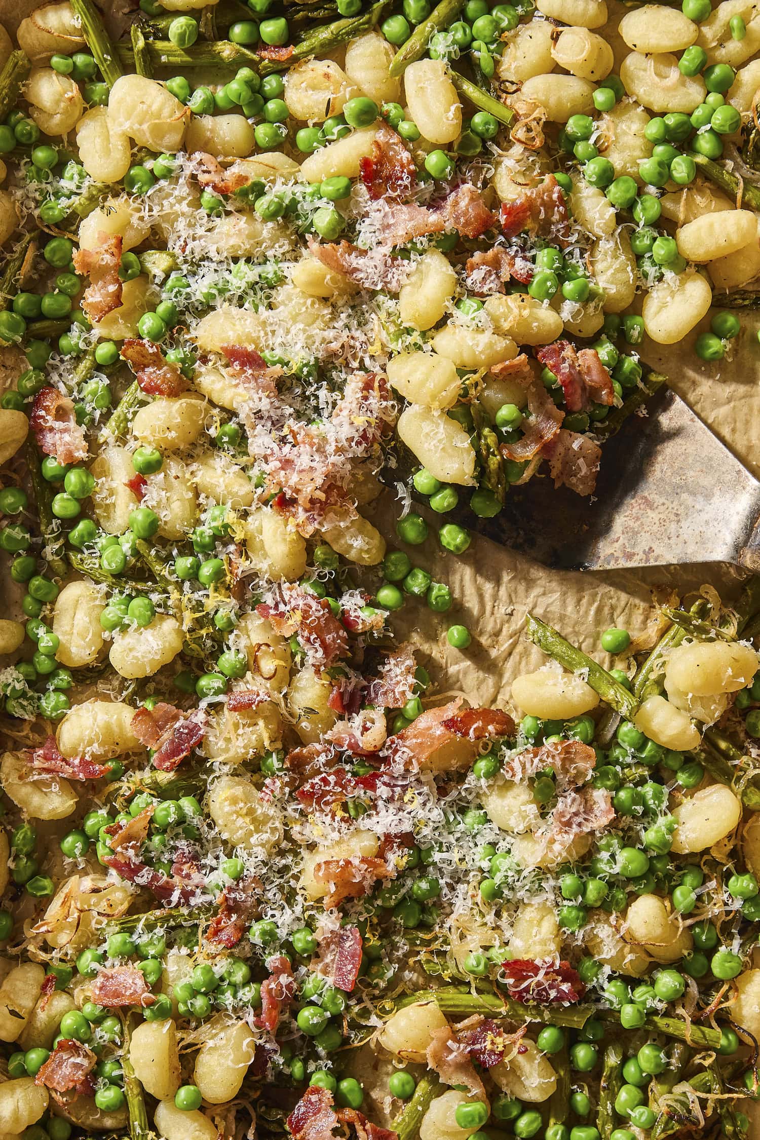 Sheet pan with gnocchi roasted with asparagus, bacon, and peas.
