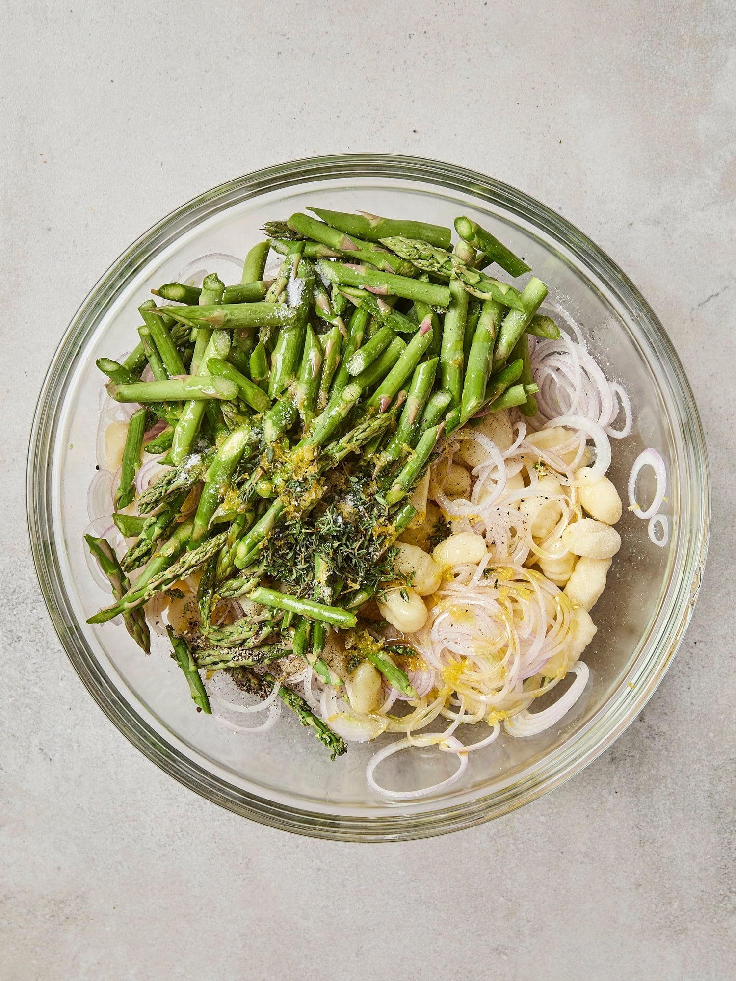 Glass bowl with gnocchi, shallot, and asparagus.