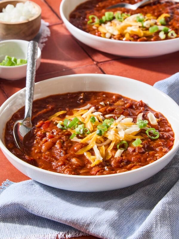 Bowl of vegetarian chili with toppings and spoon.