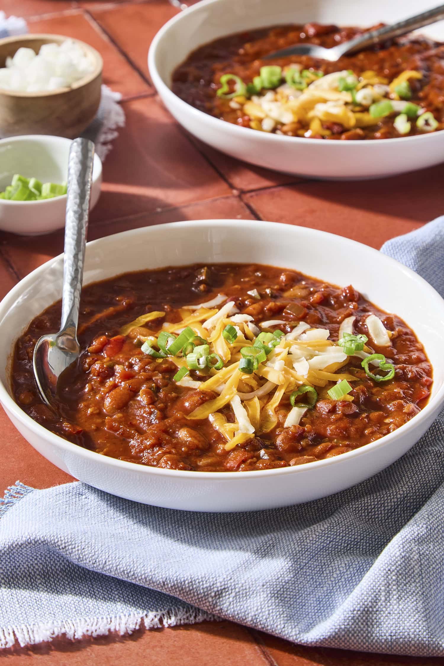 Bowl of vegetarian chili with toppings and spoon.