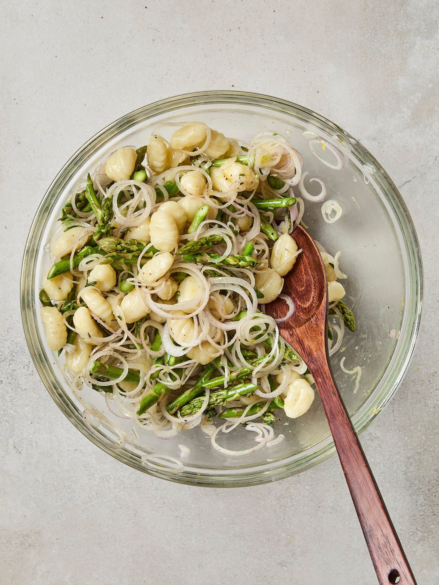 Glass bowl with mixture of gnocchi with vegetables.