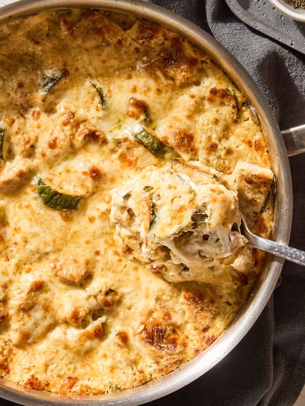 Cheesy chicken casserole with zucchini with spoonful scooping.