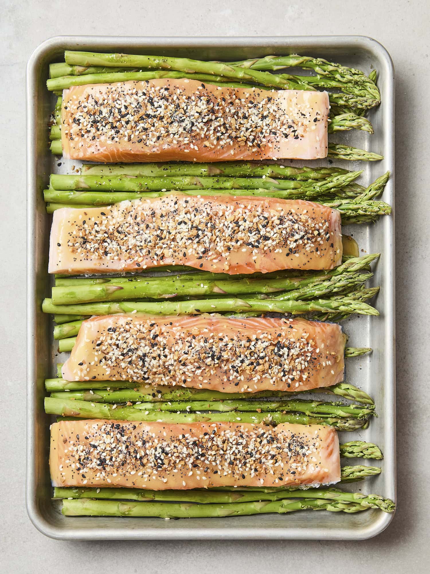 Uncooked salmon fillets with everything bagel seasoning on top.