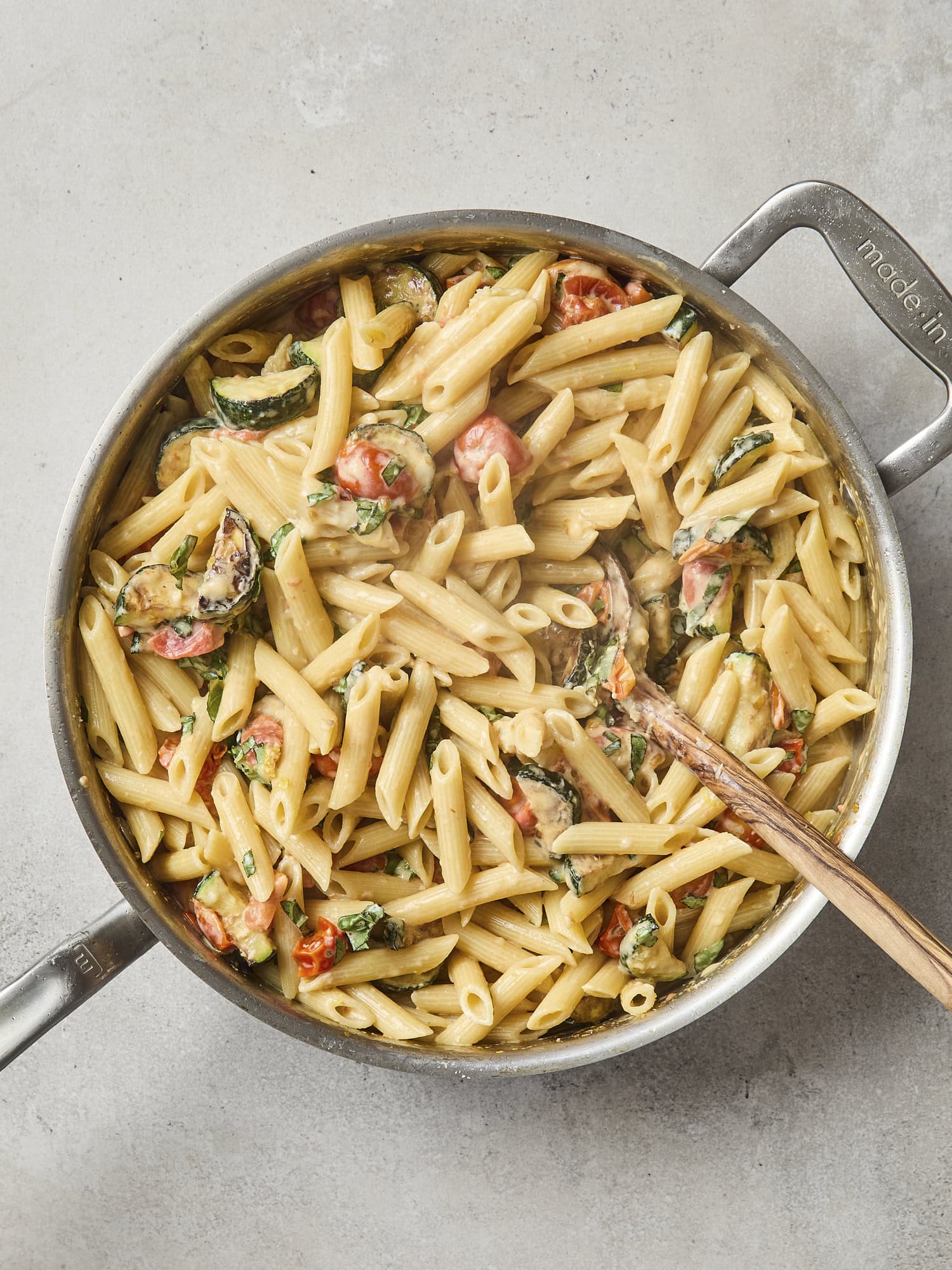 Mixture of creamy pasta with zucchini and tomatoes.