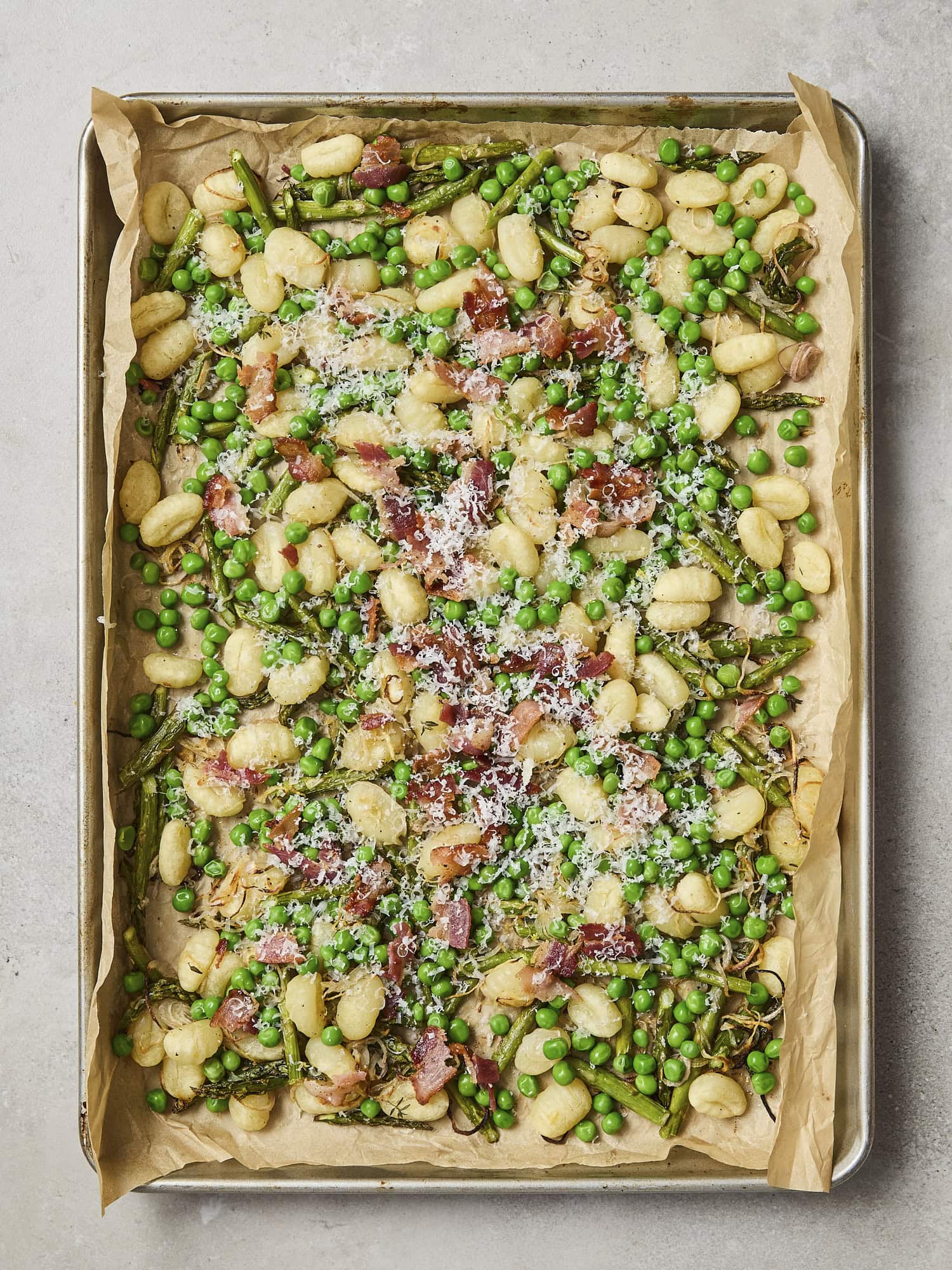Sheet pan gnocchi with asparagus with bacon and Parmesan cheese.