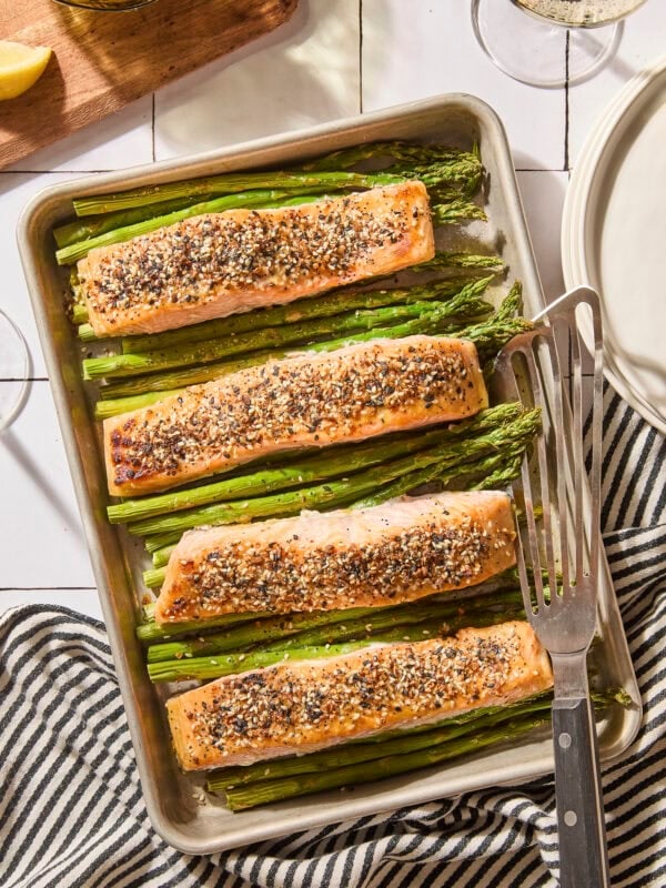 Sheet pan with pieces of cooked salmon on top of asparagus.