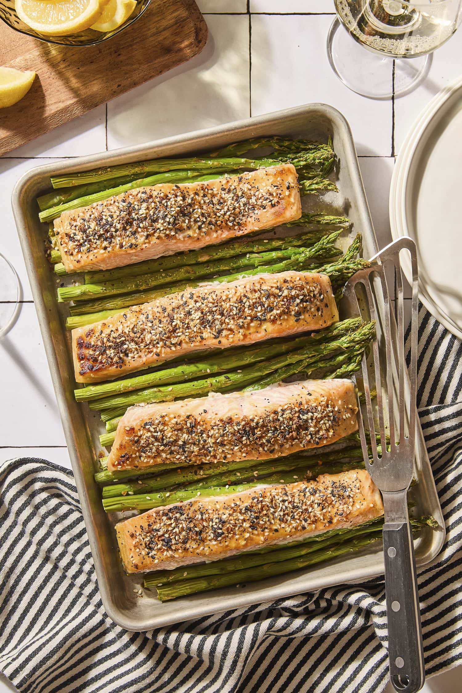 Sheet pan with pieces of cooked salmon on top of asparagus.