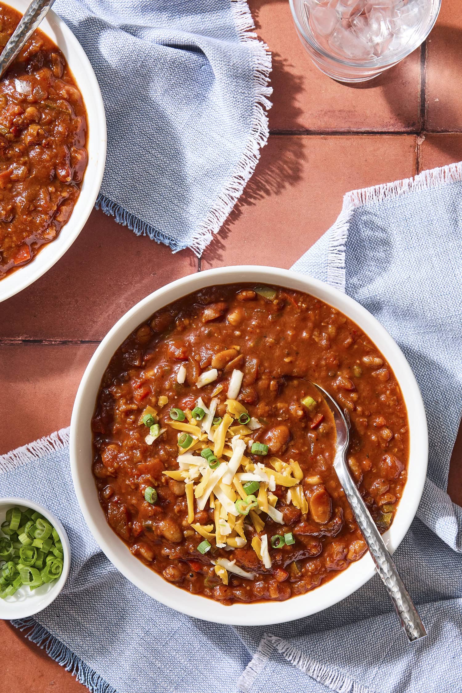 Bowl of vegetarian chili topped with cheese and scallions.
