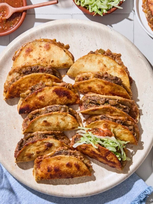 Crispy baked beef tacos sitting on platter with golden edges.