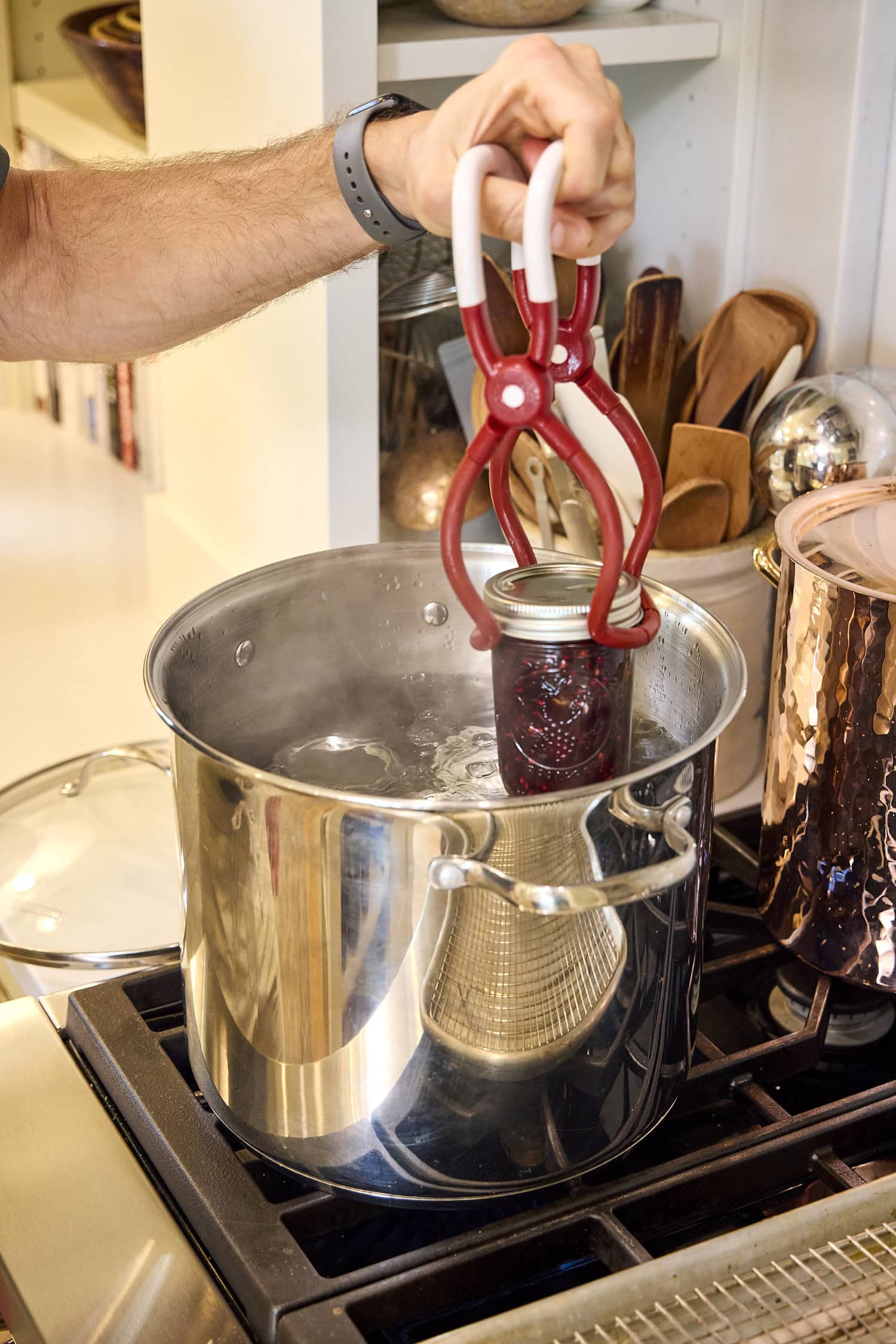 Jar with blackberry jam going into water bath canner.