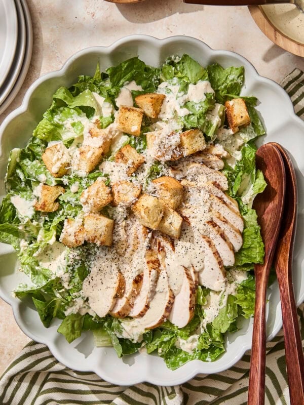 Chicken Caesar salad with croutons and dressing on top in bowl.