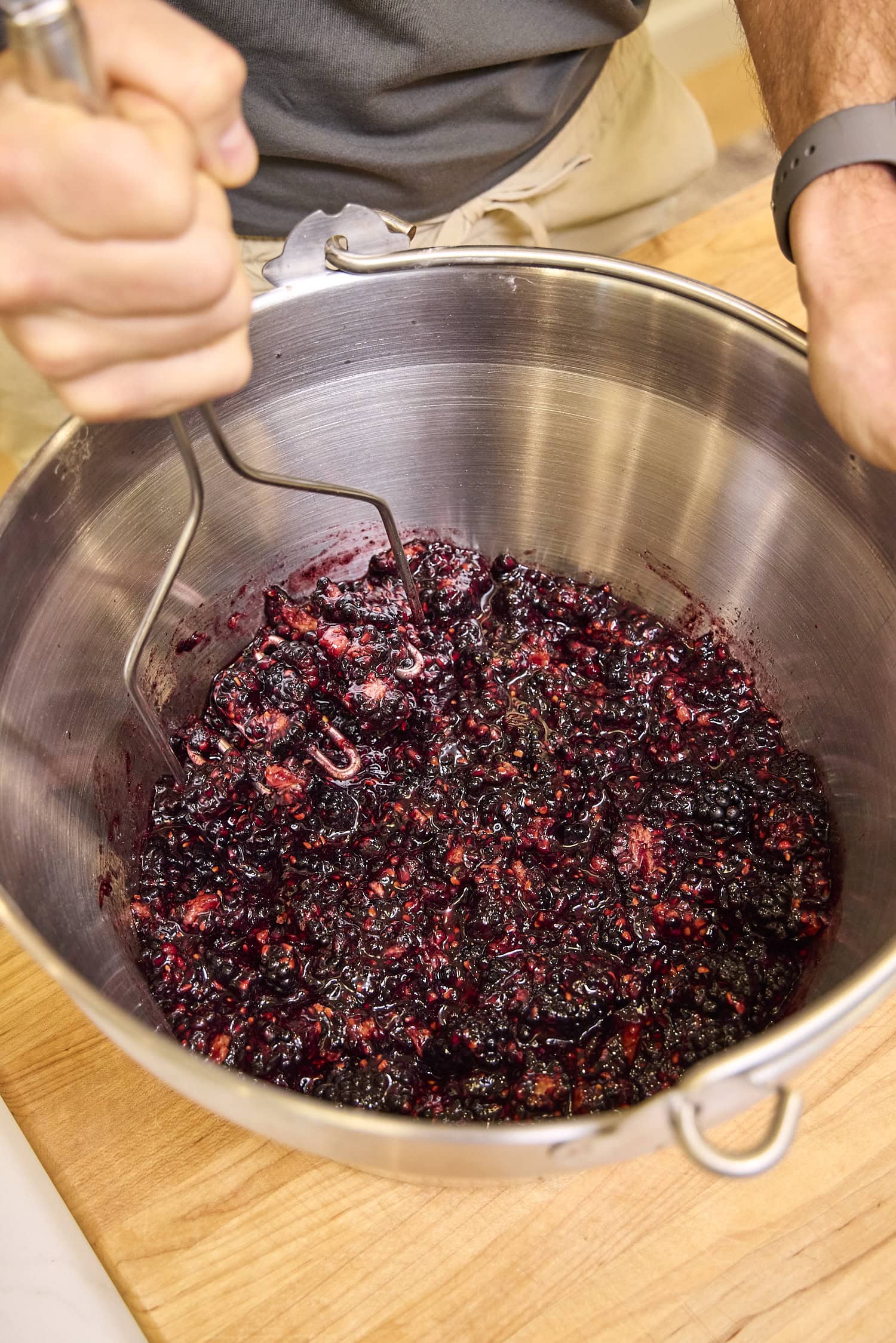 Using masher to mash blackberries for a homemade jam recipe.