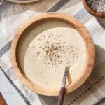 Bowl with homemade Caesar dressing with black pepper sprinkled on top.