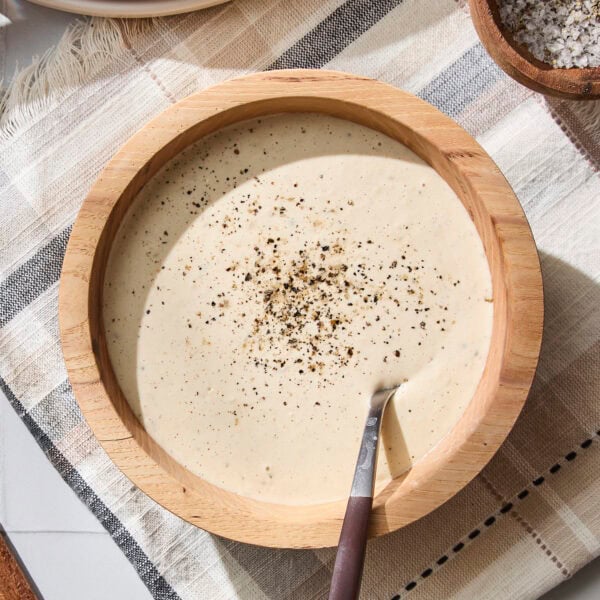 Bowl with homemade Caesar dressing with black pepper sprinkled on top.