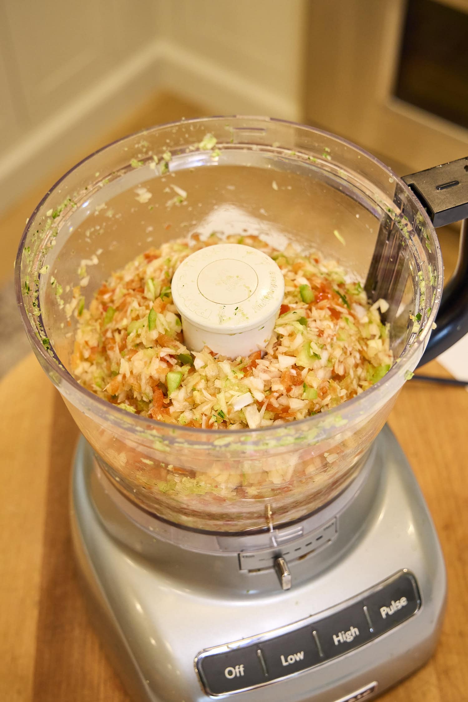 Food processor with chopped vegetables for zucchini relish.
