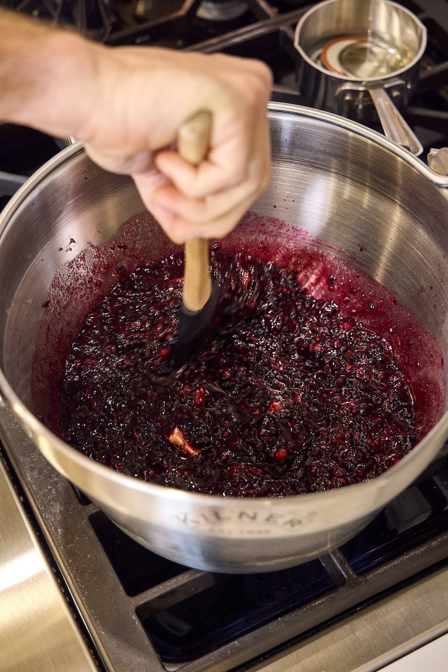 Stirring blackberry jam mixture on stovetop.