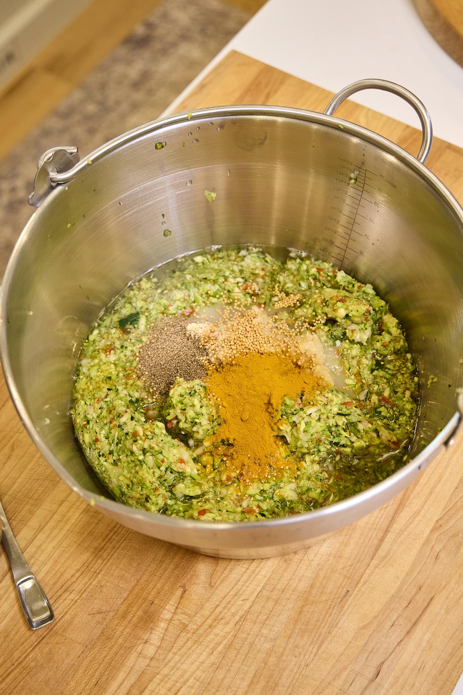 Large pot with chopped zucchini and spices before cooking.