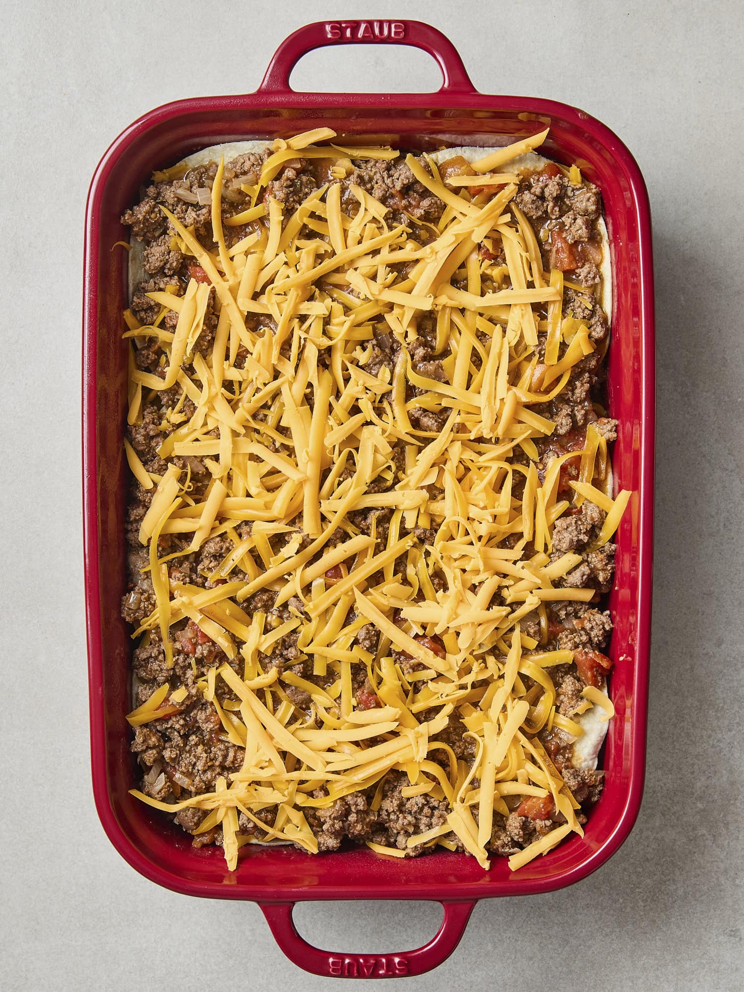 Unbaked taco casserole with cheese on top.