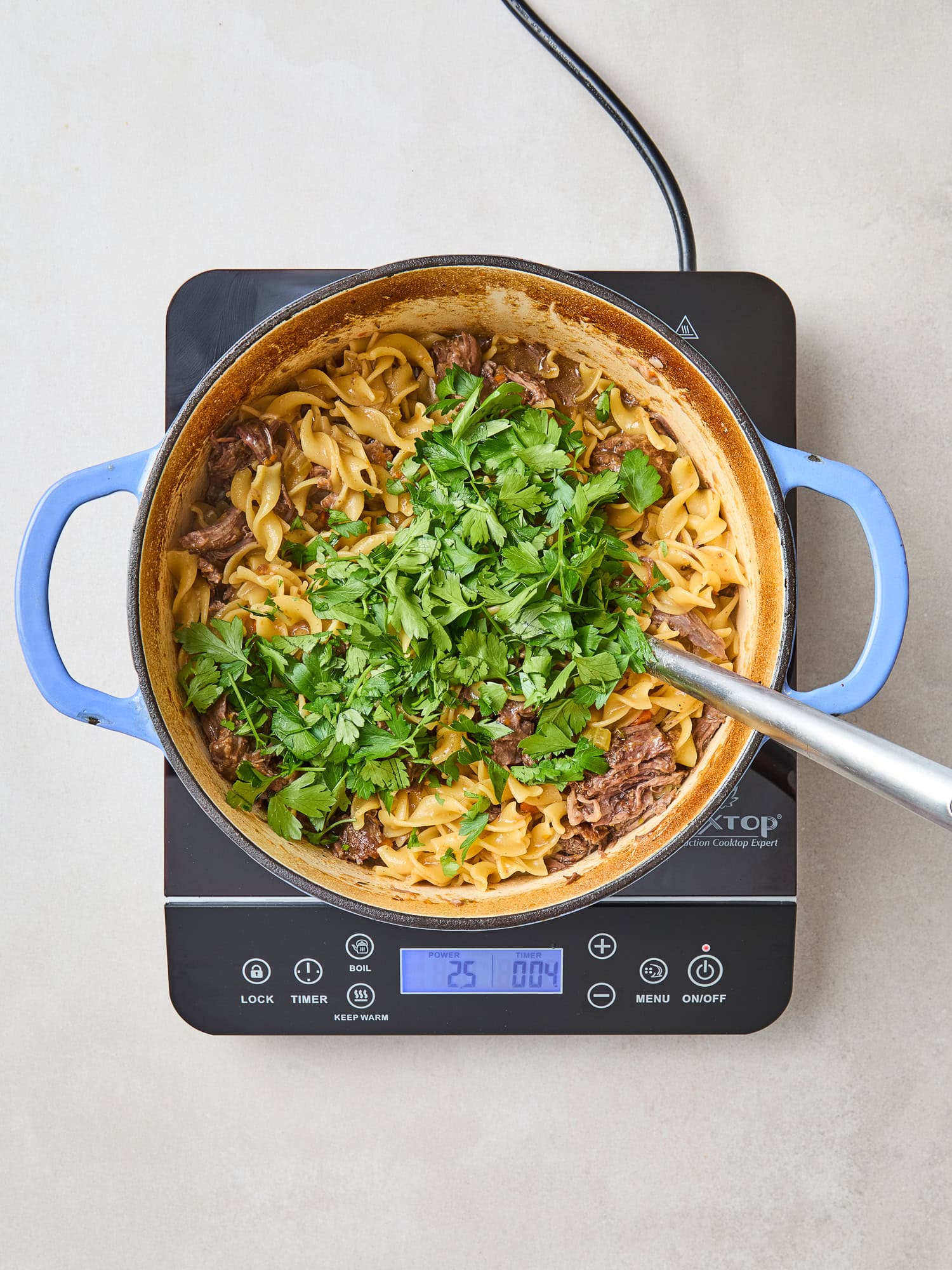 Fresh parsley added to a finished beef and noodle dish.