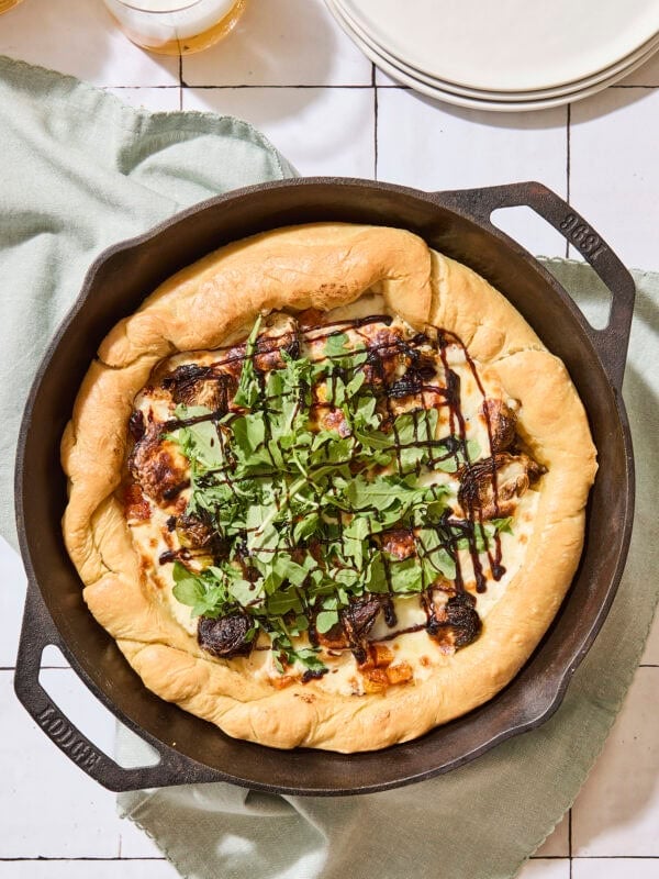 Baked butternut squash pizza in skillet topped with arugula.