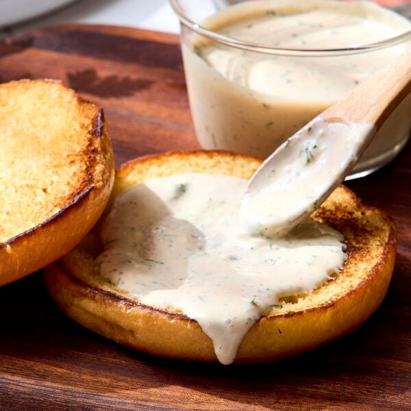 Bun with spoon spreading creamy Dijon herb sauce on top.