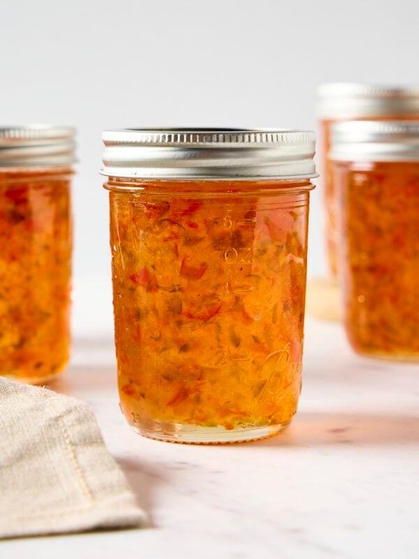 Jam jars filled with orange-colored hot pepper jelly recipe.