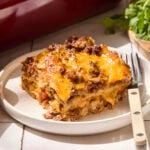 Slice of taco casserole with cheese on top sitting on a plate.