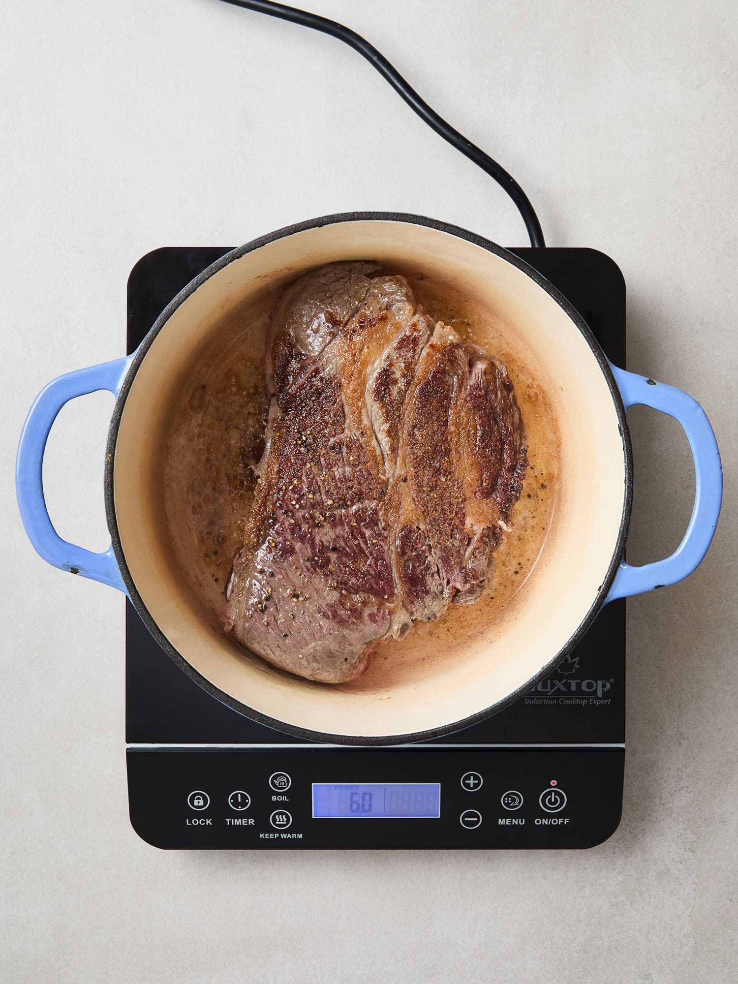 Chuck roast searing in a Dutch oven for beef and noodles.