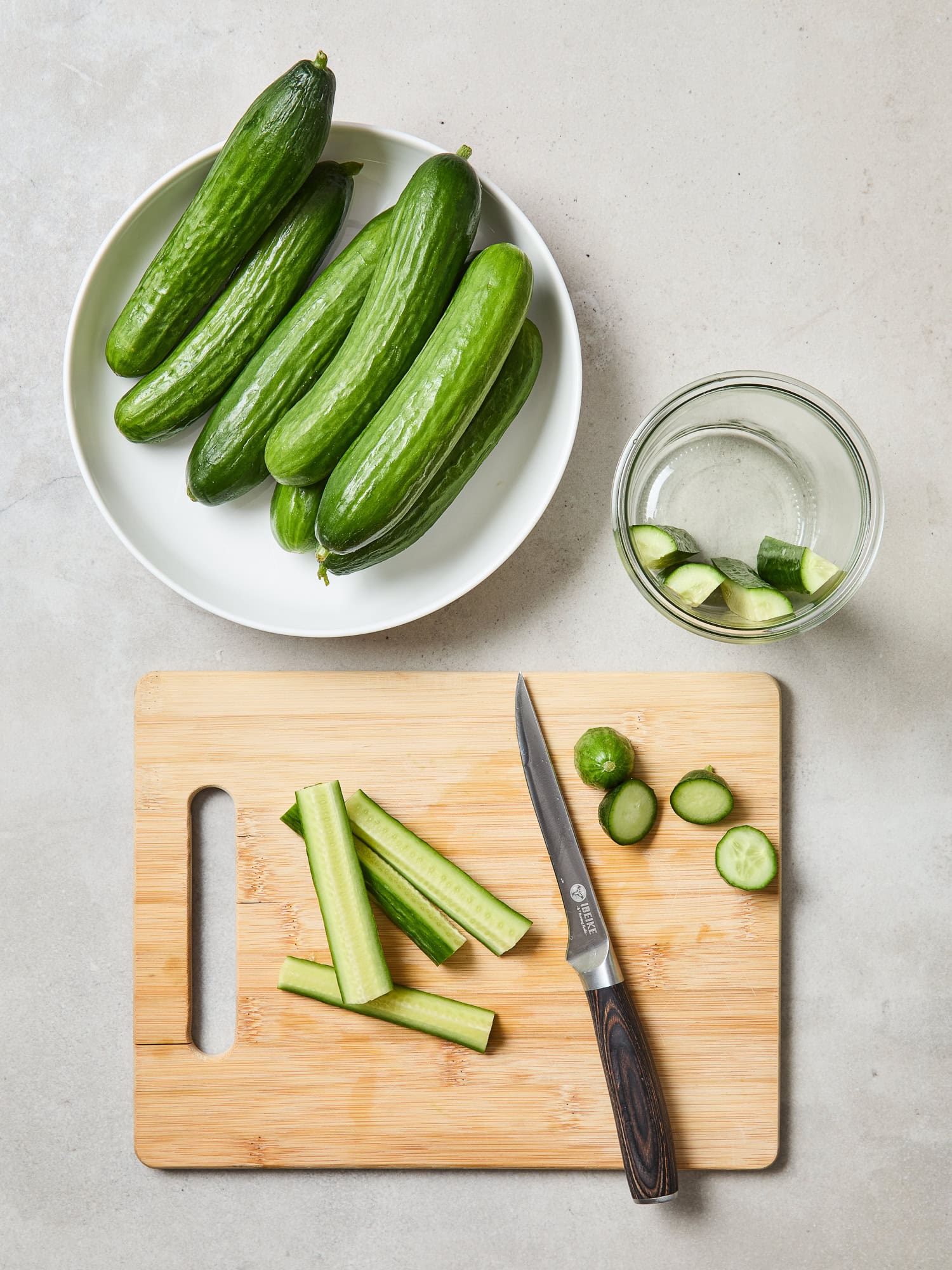 Sliced cucumbers scattered around a cutting board prior to pickling.