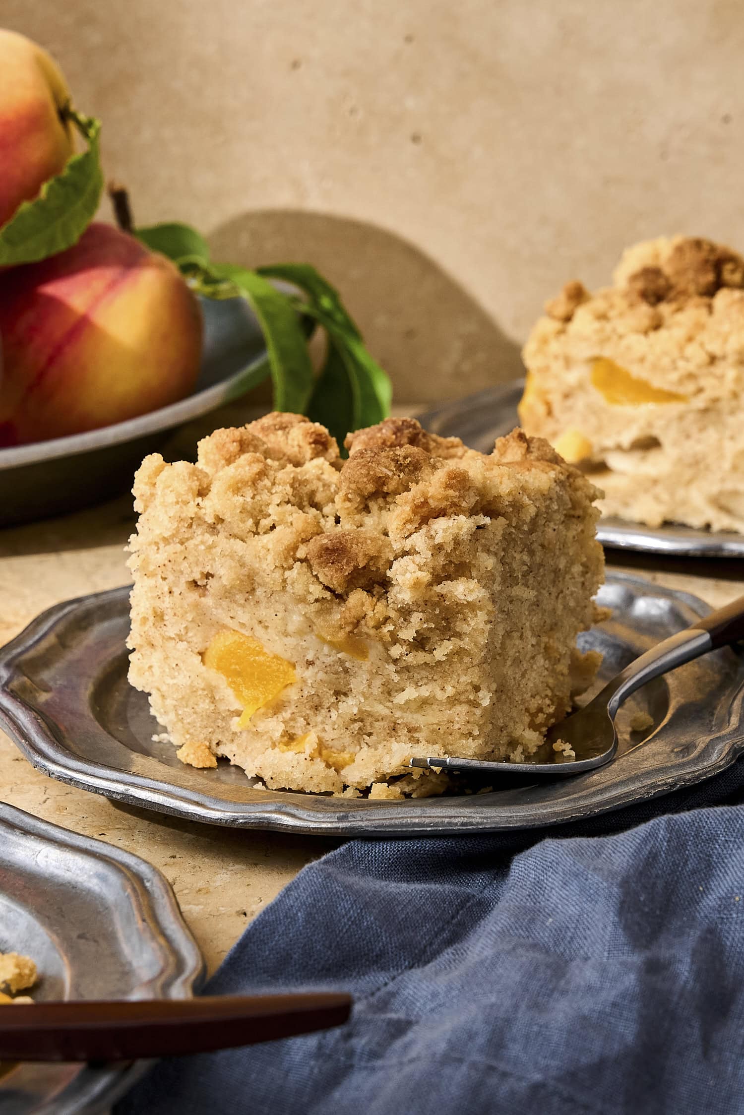 Slice of peach coffee cake on pewter plate.