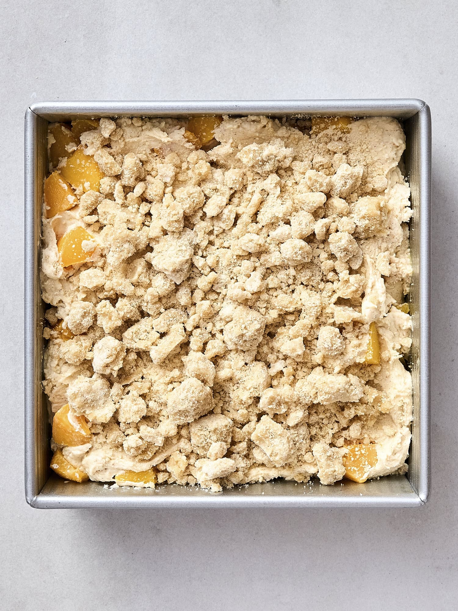 Unbaked peach coffee cake with crumble topping.